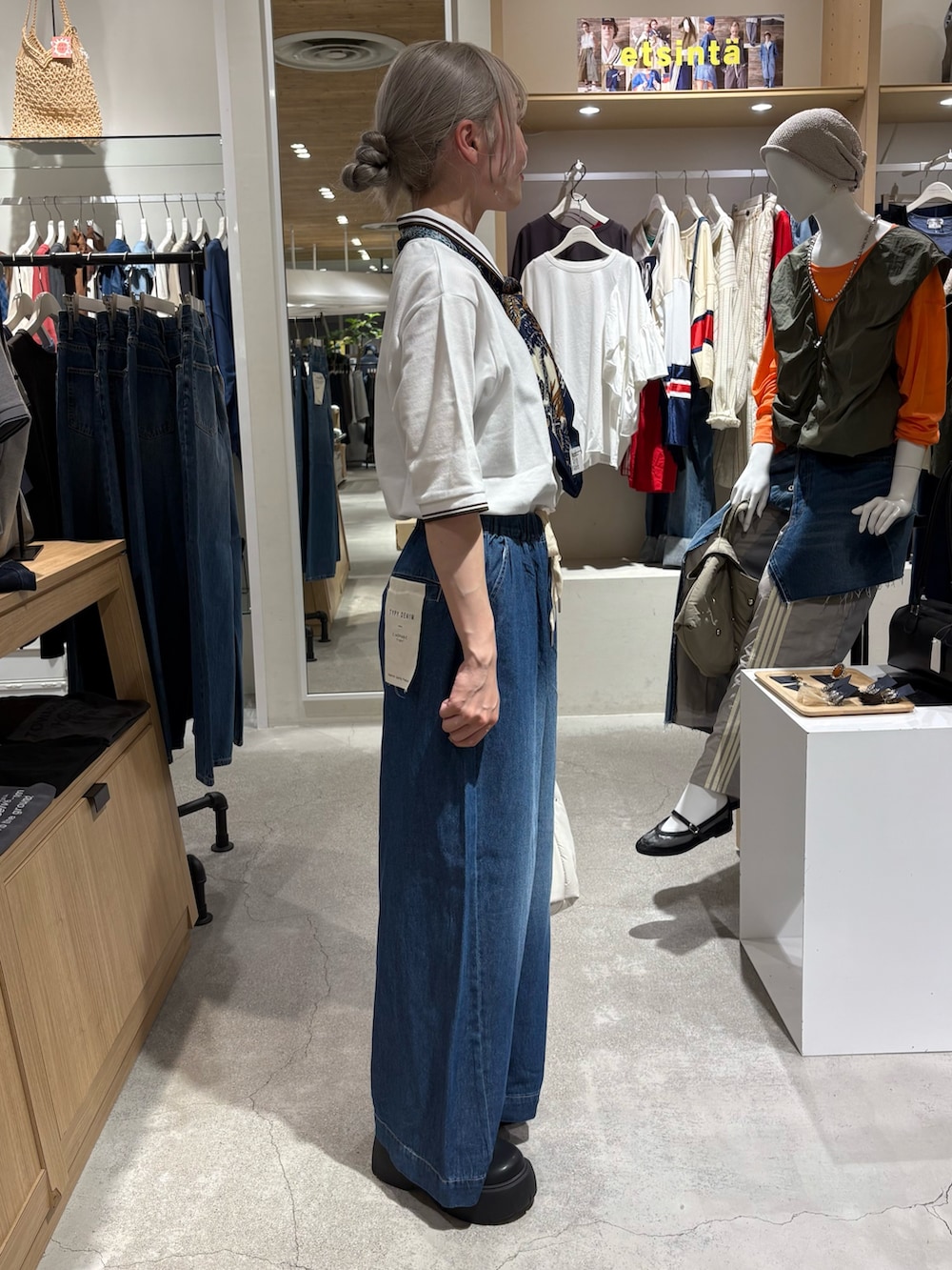 ホワイト系のポロシャツ、ブルー系のデニムパンツ、ブラック系のブーツを着用したレディースの夏コーディネートの3枚目の写真