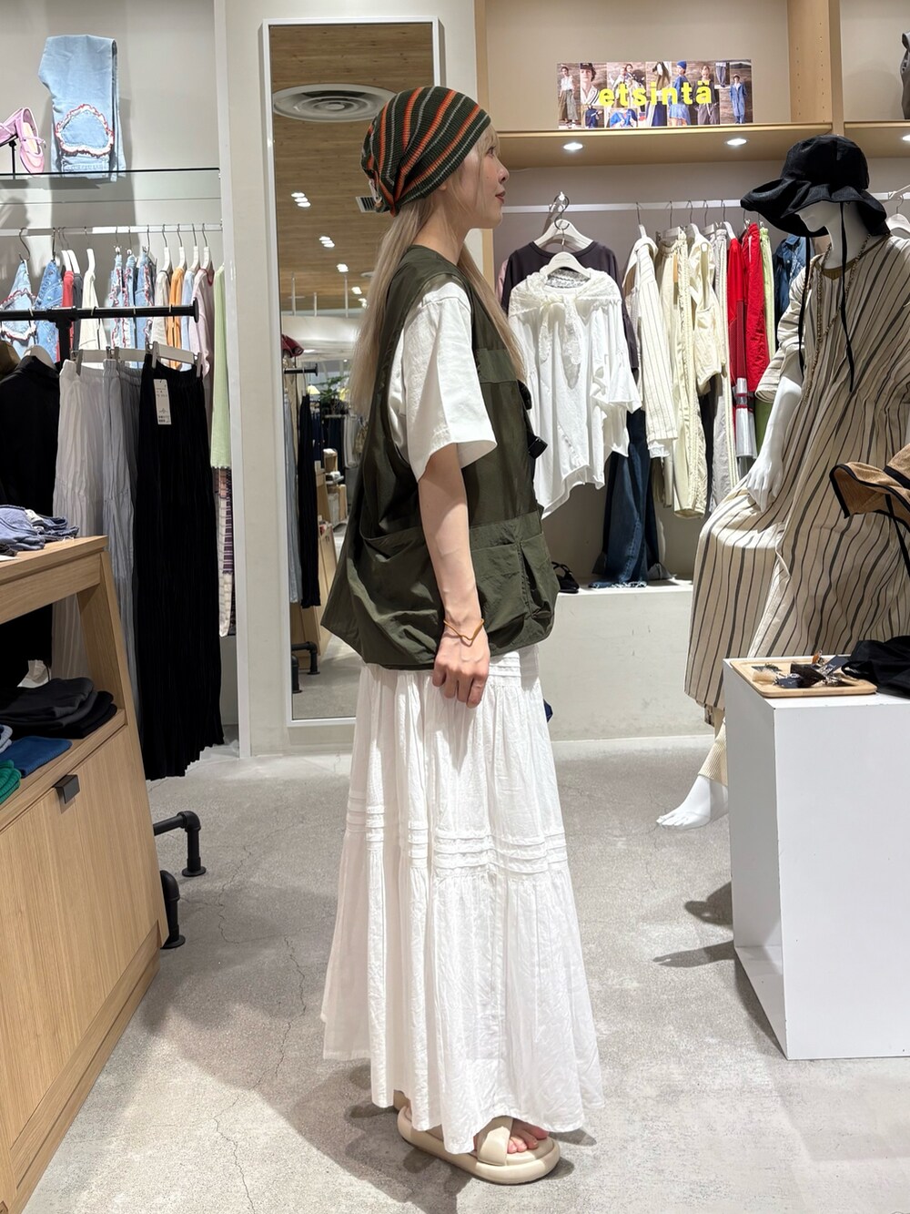 グリーン系のベスト、ホワイト系のTシャツ/カットソー、グリーン系のバックパック/リュックを着用したレディースの夏コーディネートの4枚目の写真