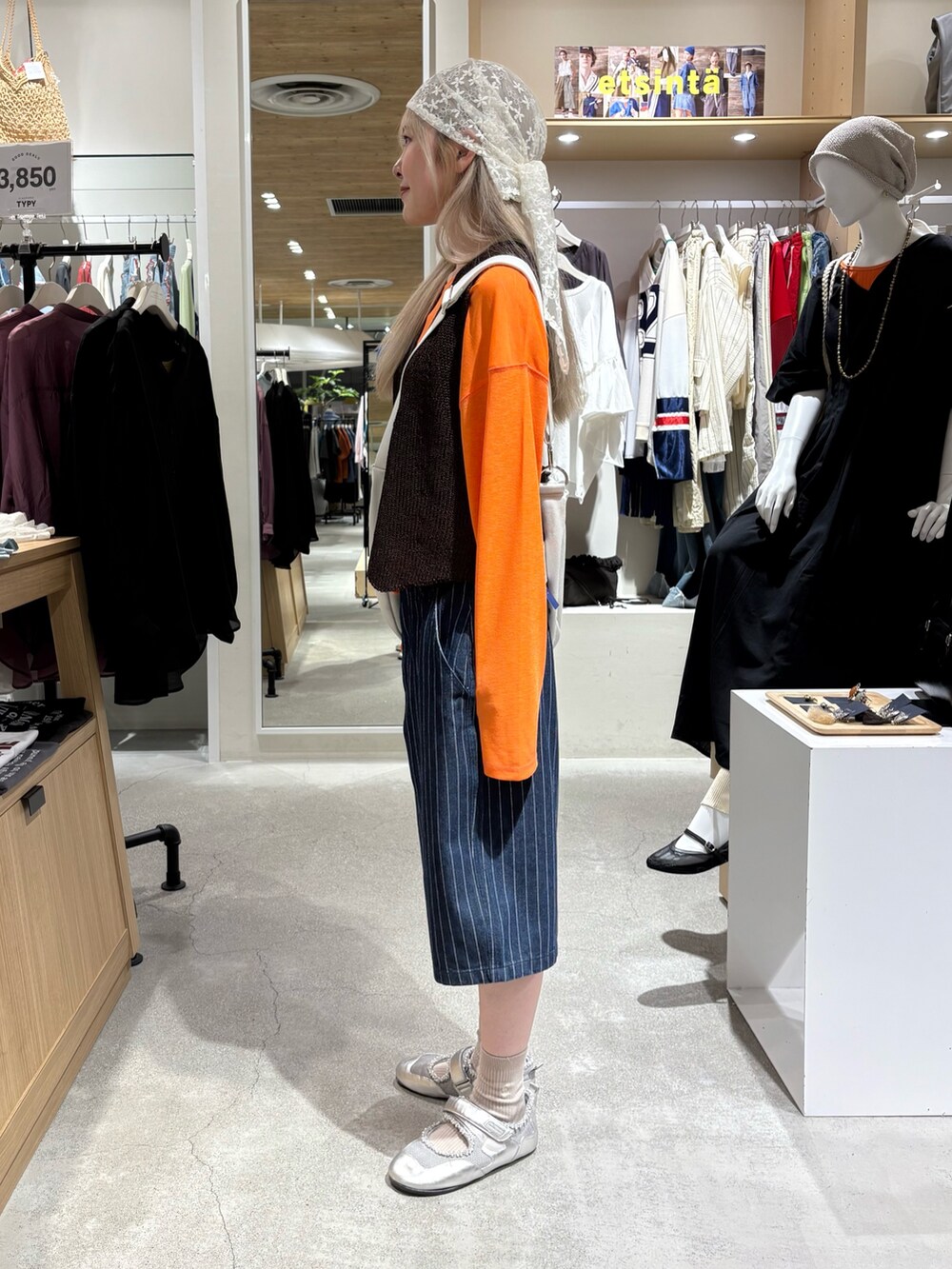 オレンジ系のTシャツ/カットソー、ブラウン系のベスト、ホワイト系のショルダーバッグを着用したレディースの夏コーディネートの2枚目の写真