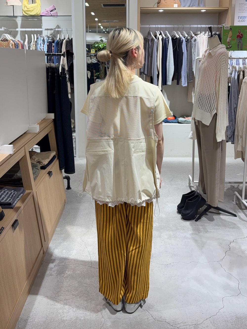 イエロー系のTシャツ/カットソー、ホワイト系のベスト、グリーン系のボディバッグ/ウエストポーチを着用したレディースの春コーディネートの3枚目の写真
