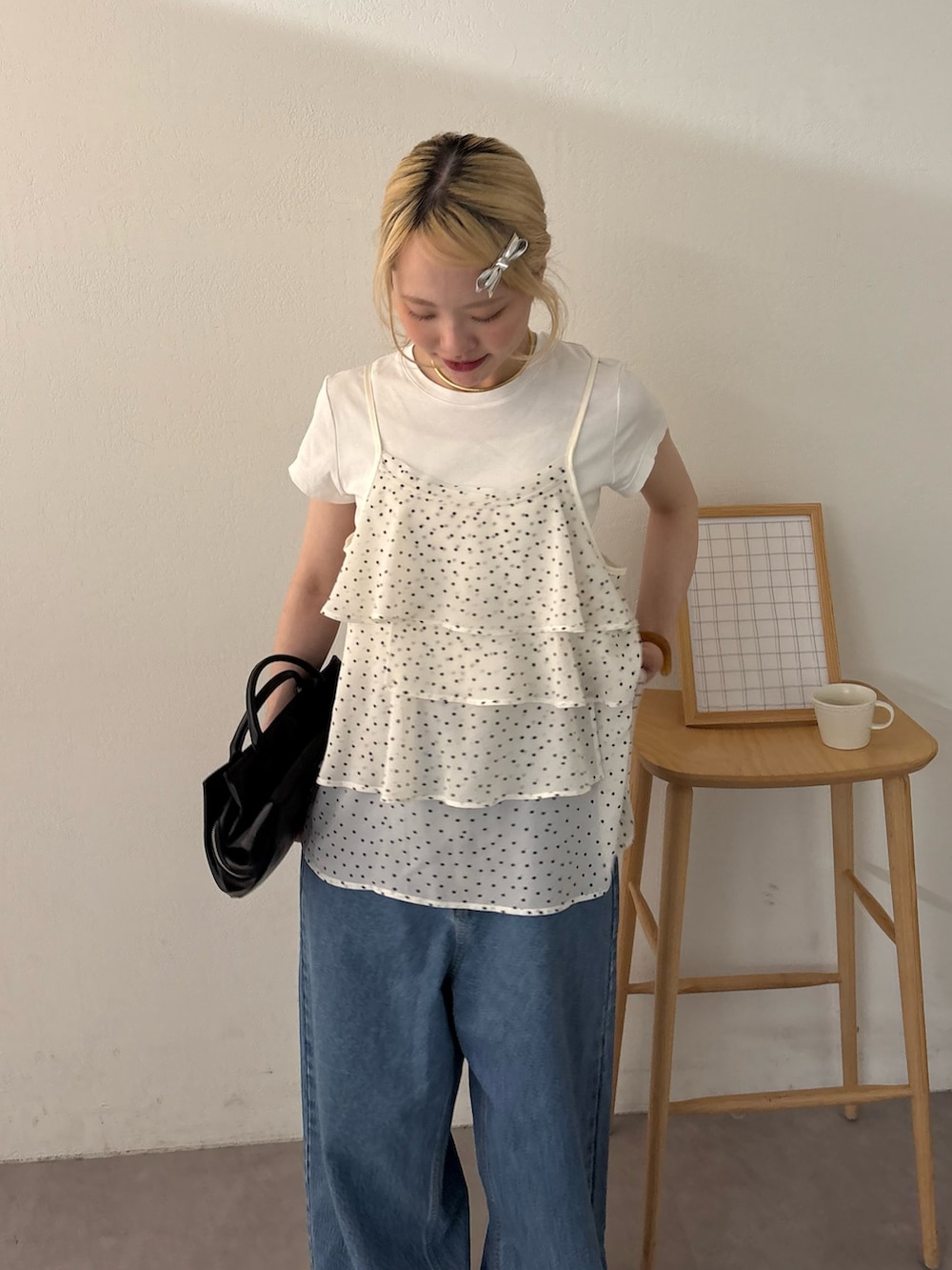 ホワイト系のキャミソール、ブラック系のショルダーバッグ、ブルー系のデニムパンツを着用したレディースの春コーディネートの3枚目の写真