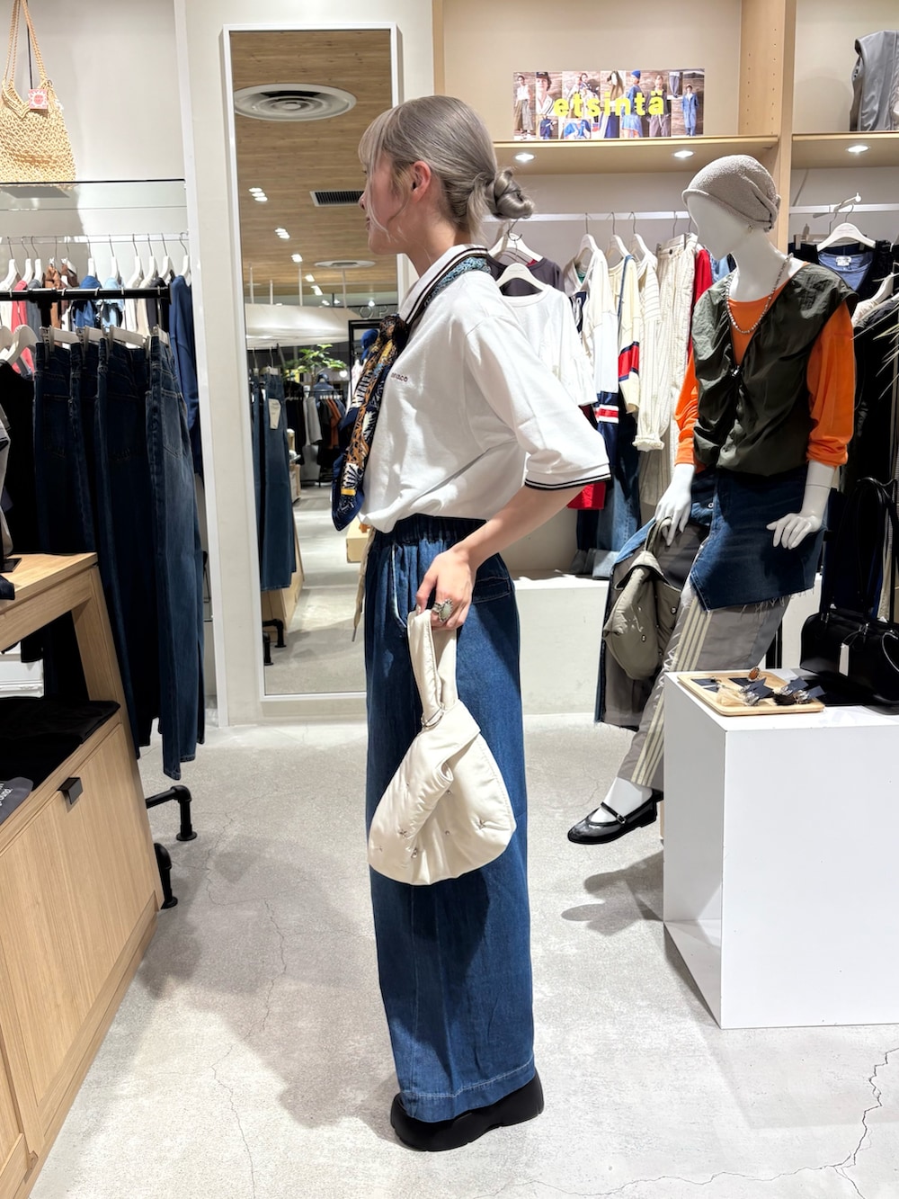 ホワイト系のポロシャツ、ブルー系のデニムパンツ、ブラック系のブーツを着用したレディースの夏コーディネートの2枚目の写真