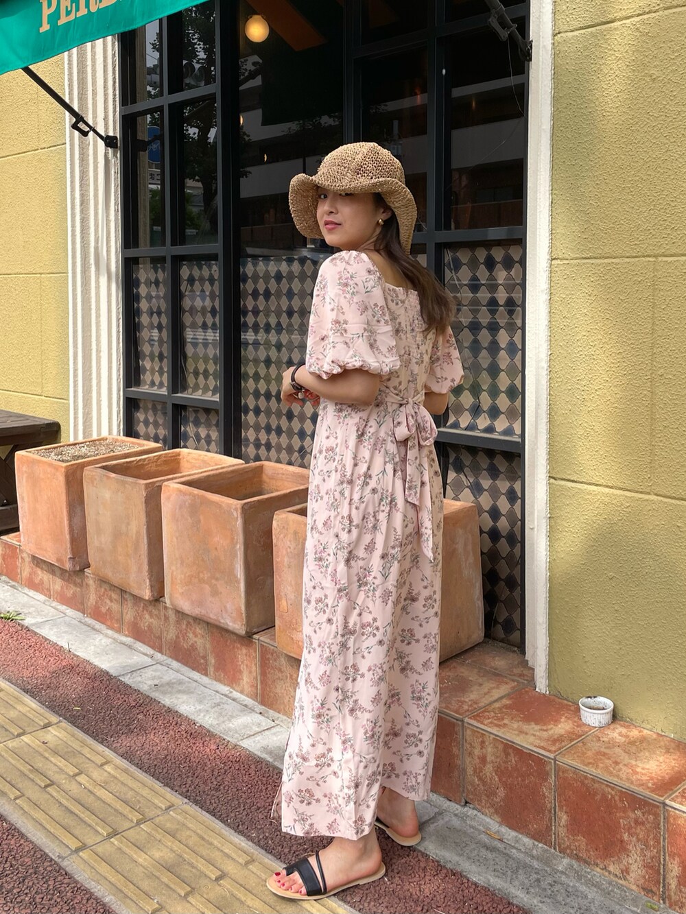 ブラック系のサンダル、ピンク系のワンピース、ベージュ系のハットを着用したレディースの春コーディネートの2枚目の写真
