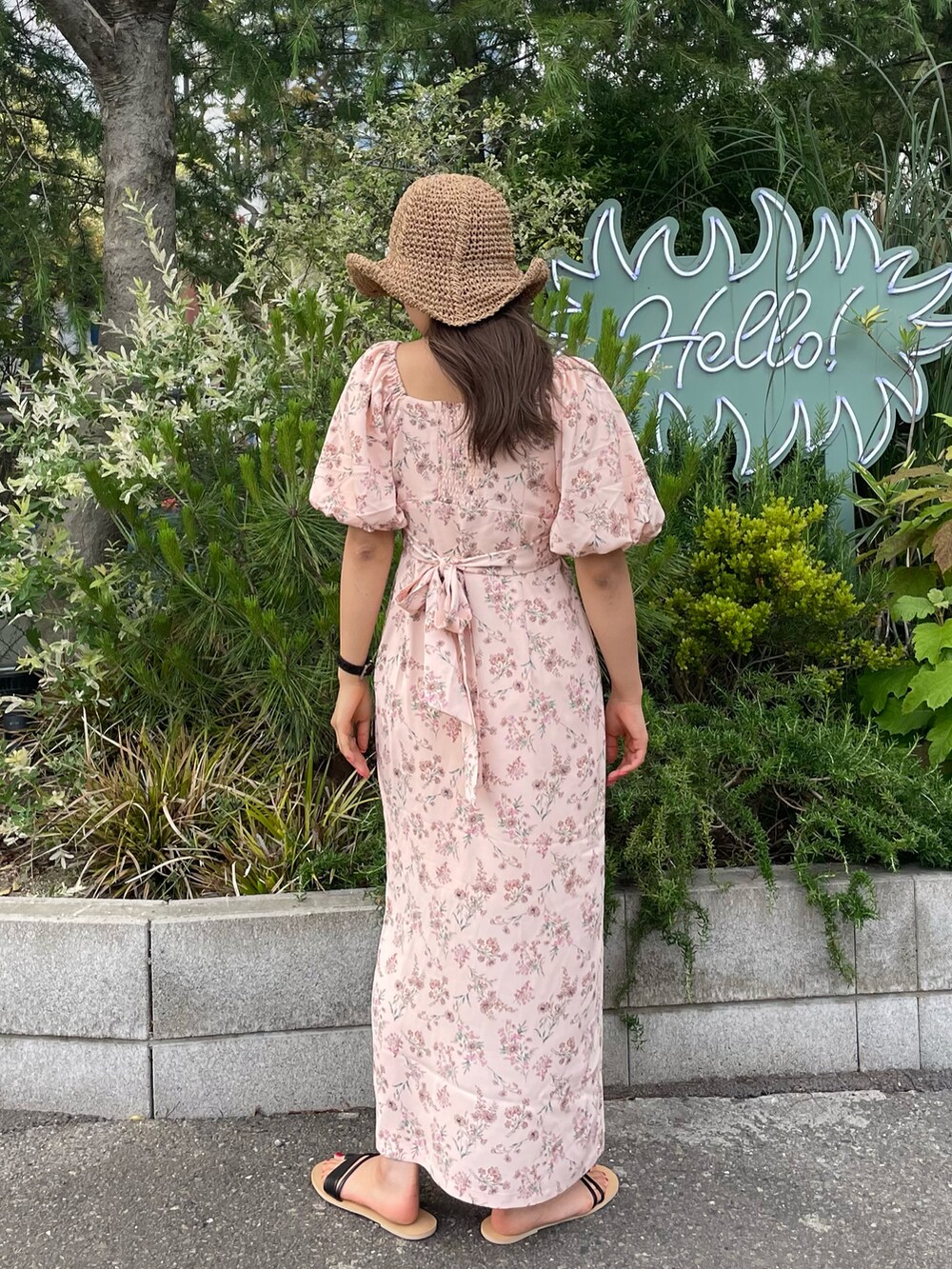 ブラック系のサンダル、ピンク系のワンピース、ベージュ系のハットを着用したレディースの春コーディネートの3枚目の写真