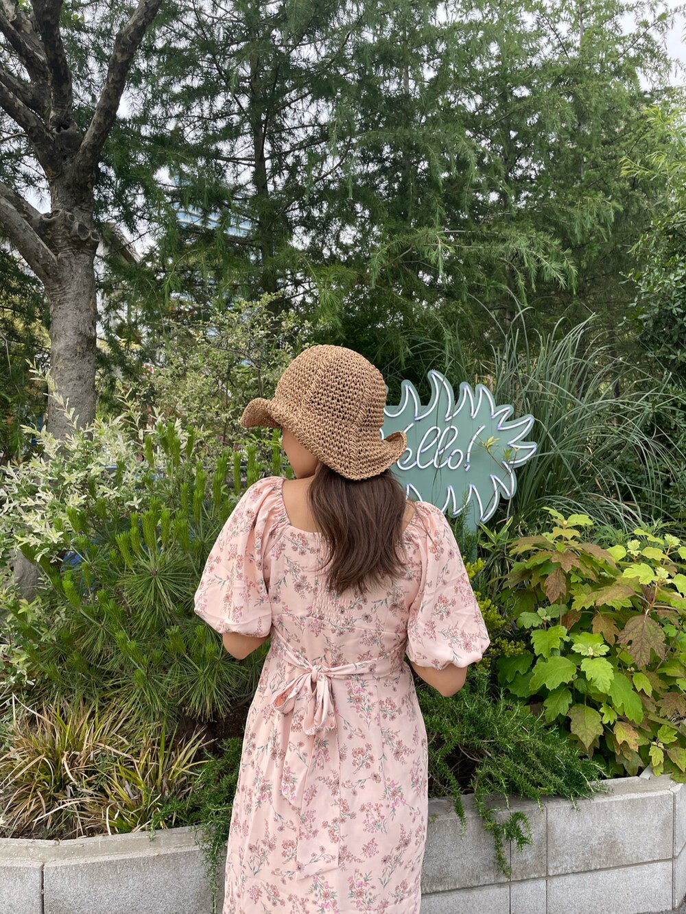 ブラック系のサンダル、ピンク系のワンピース、ベージュ系のハットを着用したレディースの春コーディネートの5枚目の写真