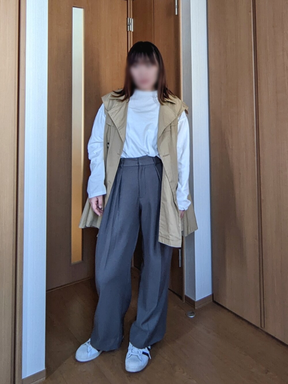 グレー系のパンツ、ホワイト系のシューズ、イエロー系のトレンチコートを着用したレディースの春コーディネートの2枚目の写真