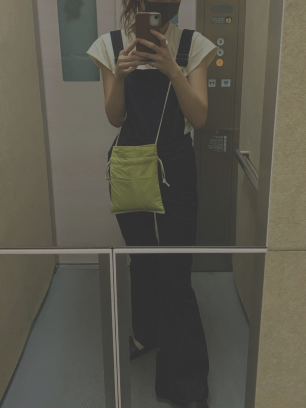 イエロー系のトートバッグ、ホワイト系のTシャツ/カットソー、ブラック系のサロペット/オーバーオールを着用したレディースの春コーディネートの2枚目の写真