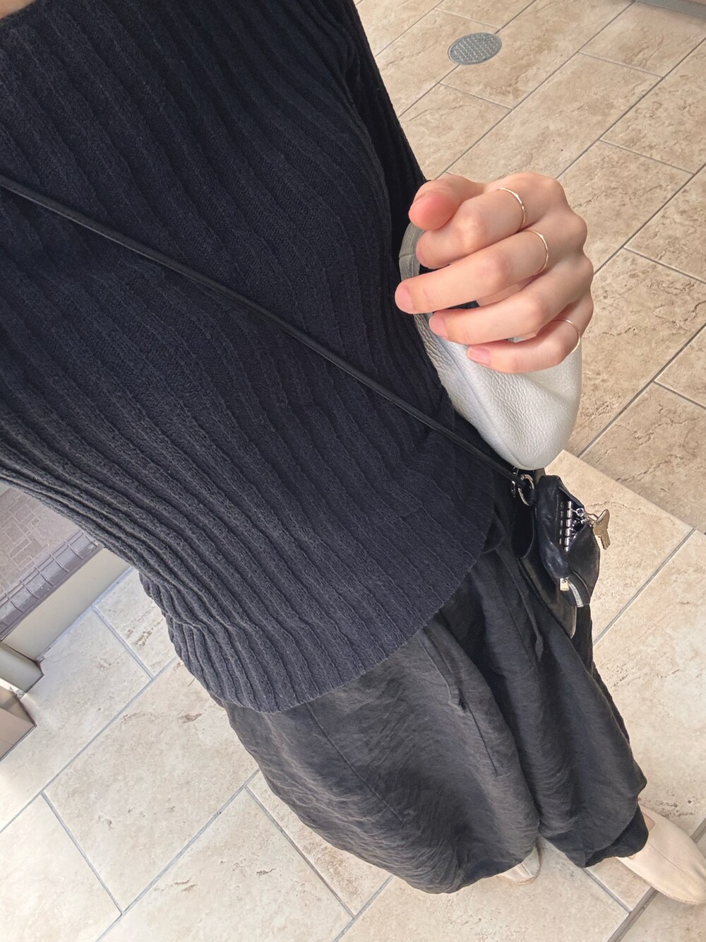 ブラック系のトップス、ホワイト系のハンドバッグ、ブラック系のパンツを着用したレディースの夏コーディネートの2枚目の写真