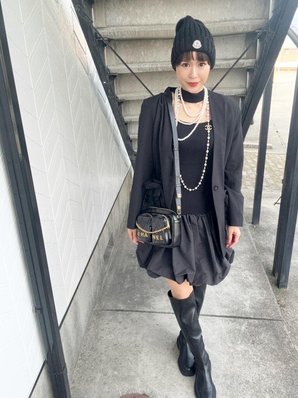 ブラック系のワンピース、ブラック系のショルダーバッグ、ホワイト系のネックレスを着用したレディースの秋コーディネートの2枚目の写真