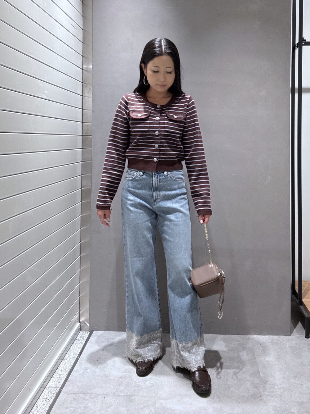 ブルー系のデニムパンツ、ブラウン系のニット/セーター、ブラウン系のローファーを着用したレディースの秋コーディネートの4枚目の写真