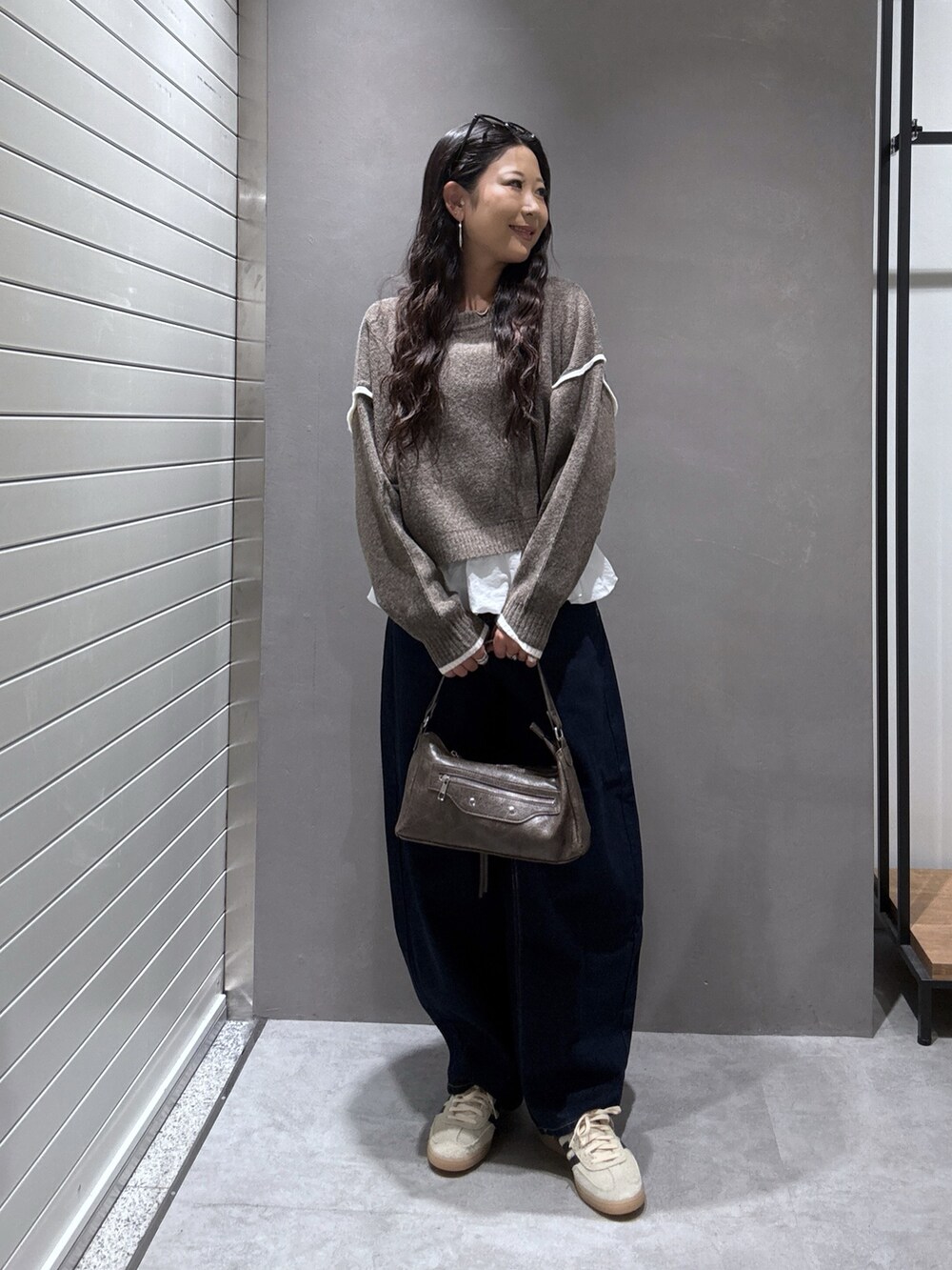 ブラウン系のニット/セーター、ブルー系のデニムパンツ、ホワイト系のTシャツ/カットソーを着用したレディースの秋コーディネートの5枚目の写真
