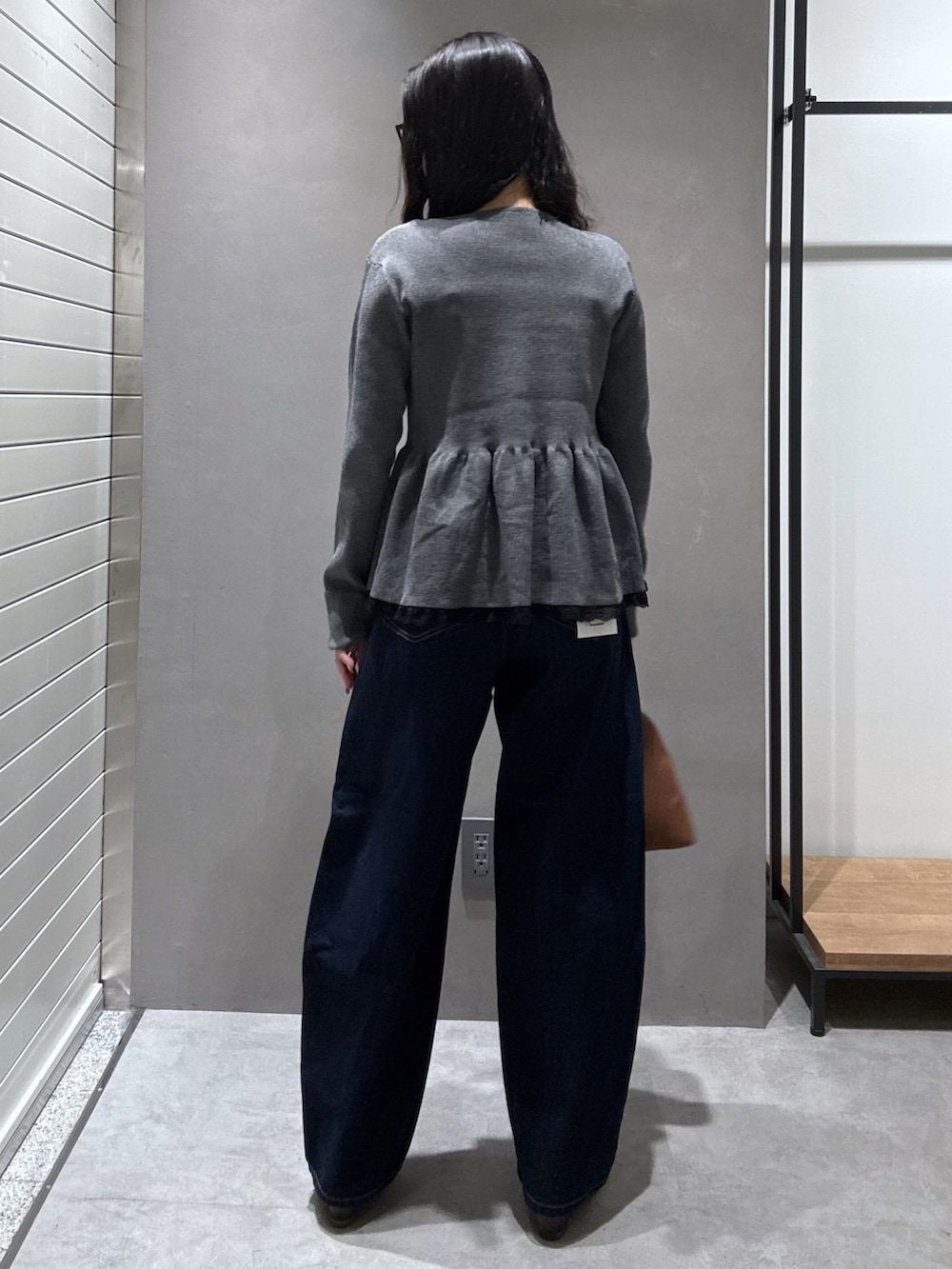 グレー系のニット/セーター、ブラウン系のショルダーバッグ、ブルー系のデニムパンツを着用したレディースの秋コーディネートの3枚目の写真