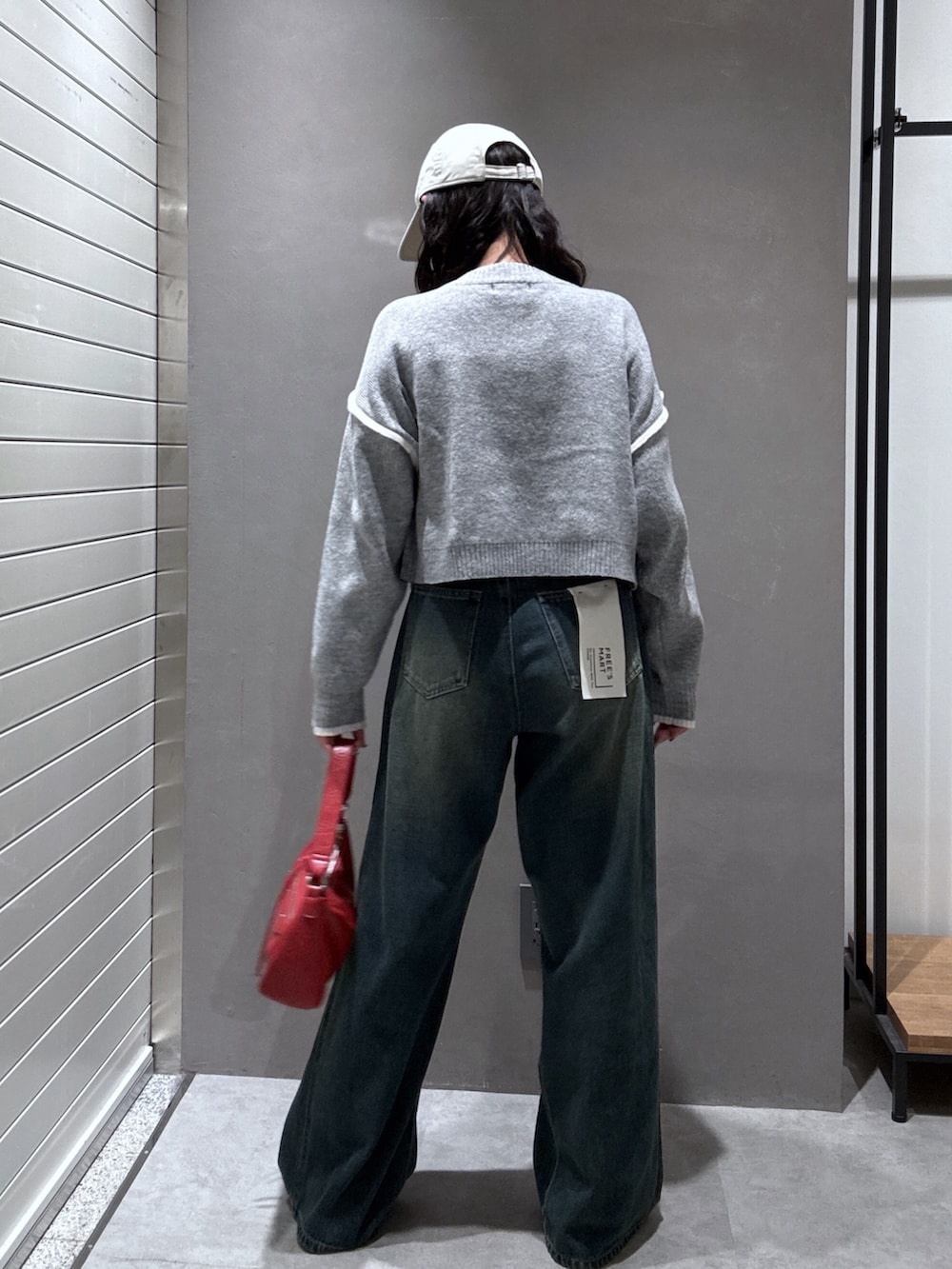 ブルー系のデニムパンツ、グレー系のニット/セーター、レッド系のショルダーバッグを着用したレディースの秋コーディネートの4枚目の写真