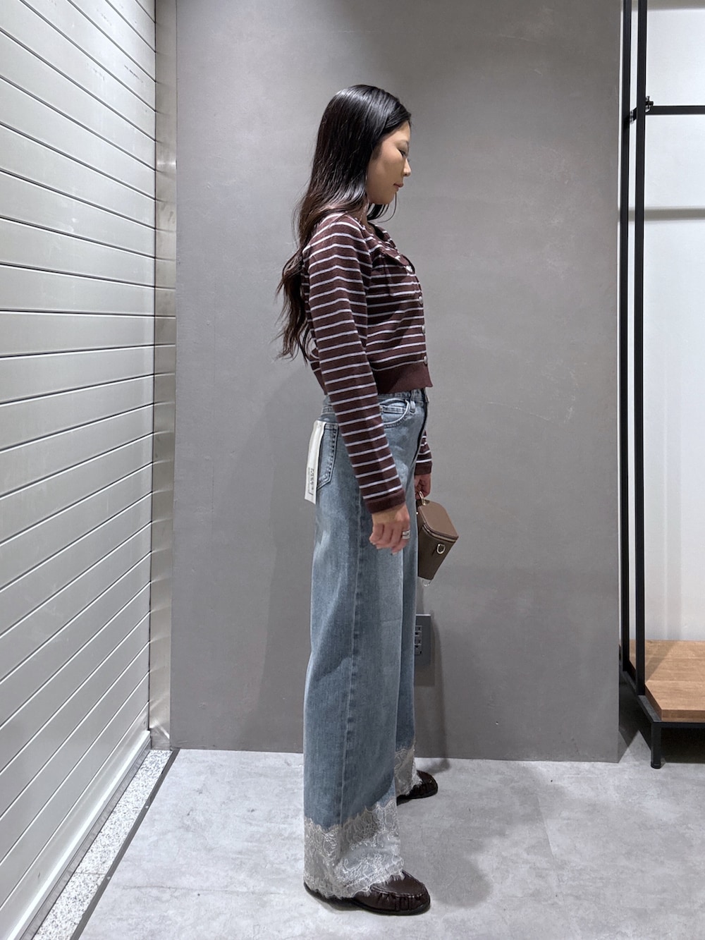 ブルー系のデニムパンツ、ブラウン系のニット/セーター、ブラウン系のローファーを着用したレディースの秋コーディネートの2枚目の写真