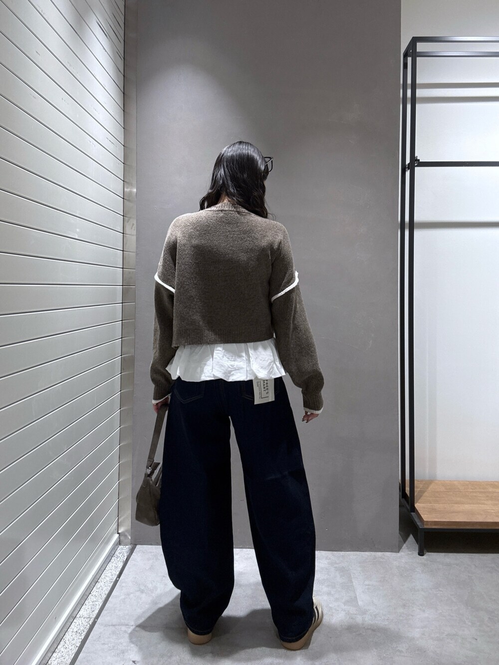 ブラウン系のニット/セーター、ブルー系のデニムパンツ、ホワイト系のTシャツ/カットソーを着用したレディースの秋コーディネートの4枚目の写真