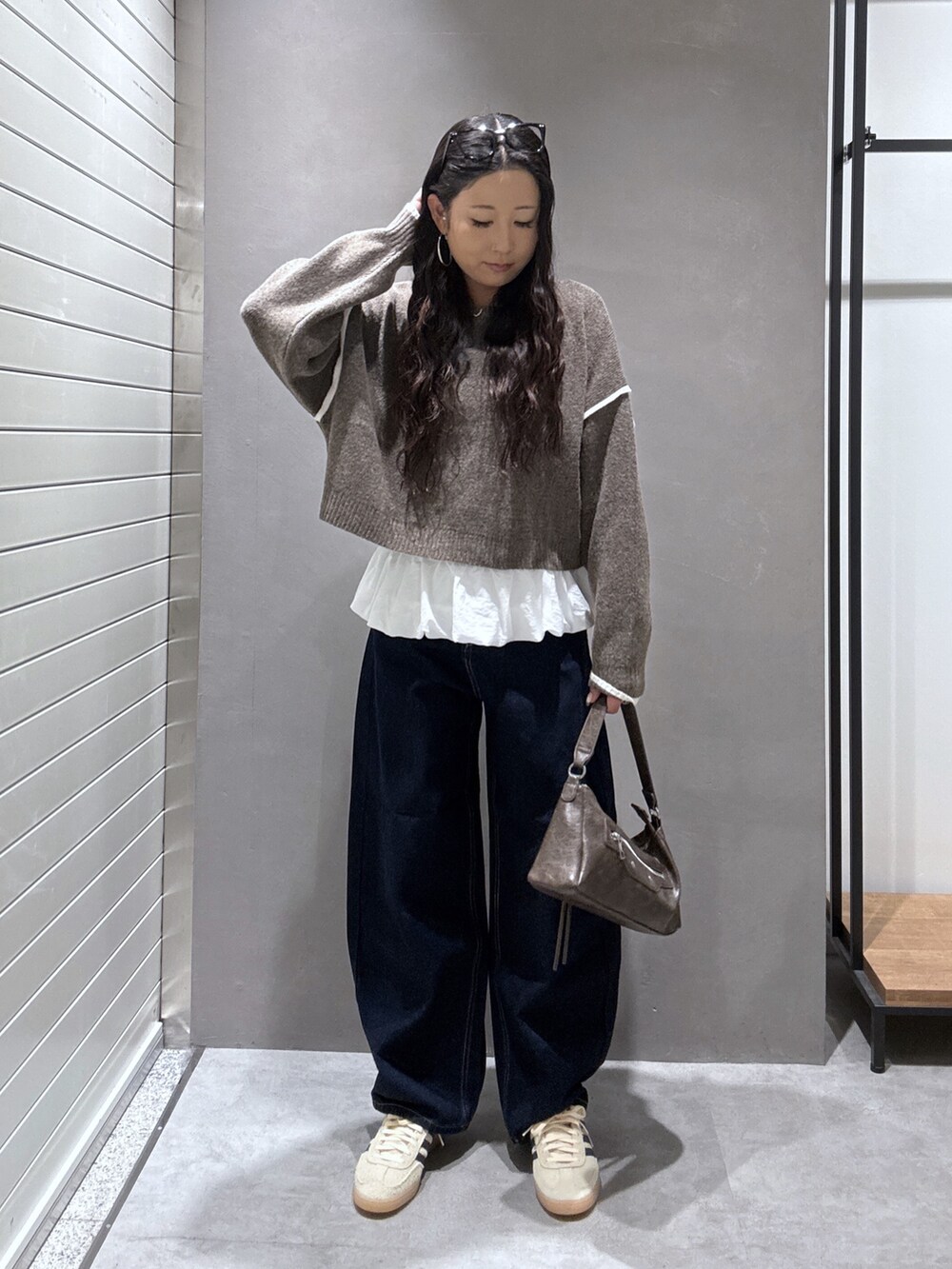 ブラウン系のニット/セーター、ブルー系のデニムパンツ、ホワイト系のTシャツ/カットソーを着用したレディースの秋コーディネートの2枚目の写真
