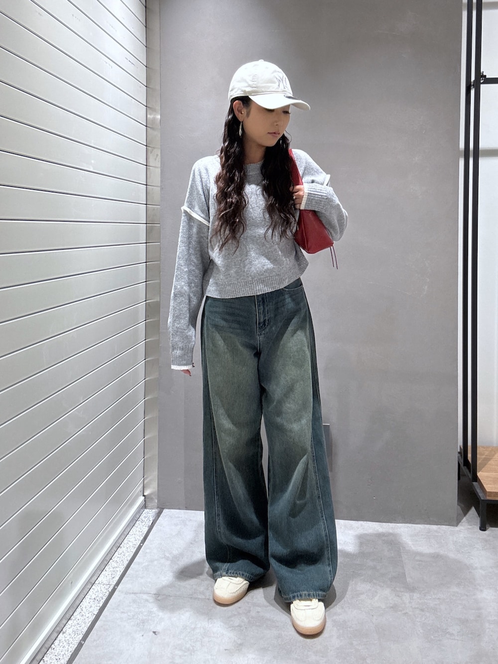 ブルー系のデニムパンツ、グレー系のニット/セーター、レッド系のショルダーバッグを着用したレディースの秋コーディネートの5枚目の写真