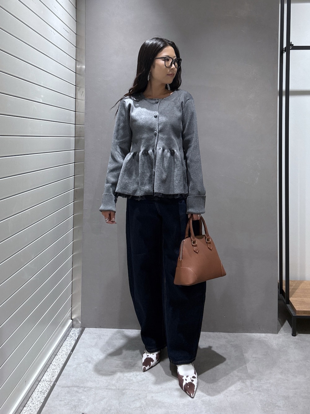 グレー系のニット/セーター、ブラウン系のショルダーバッグ、ブルー系のデニムパンツを着用したレディースの秋コーディネートの4枚目の写真
