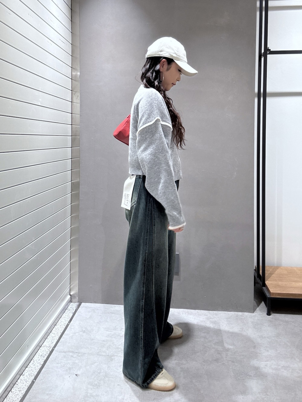 ブルー系のデニムパンツ、グレー系のニット/セーター、レッド系のショルダーバッグを着用したレディースの秋コーディネートの3枚目の写真