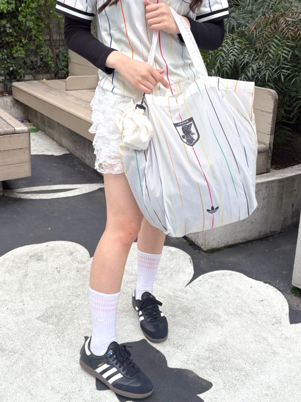 ホワイト系のTシャツ/カットソー、ホワイト系のエコバッグ/サブバッグ、ブラック系のシューズを着用したレディースの春コーディネートの2枚目の写真