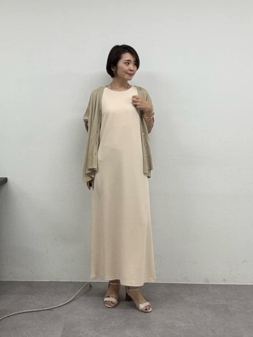ベージュ系のカーディガン/ボレロ、ホワイト系のワンピースを着用したレディースの春コーディネートの3枚目の写真