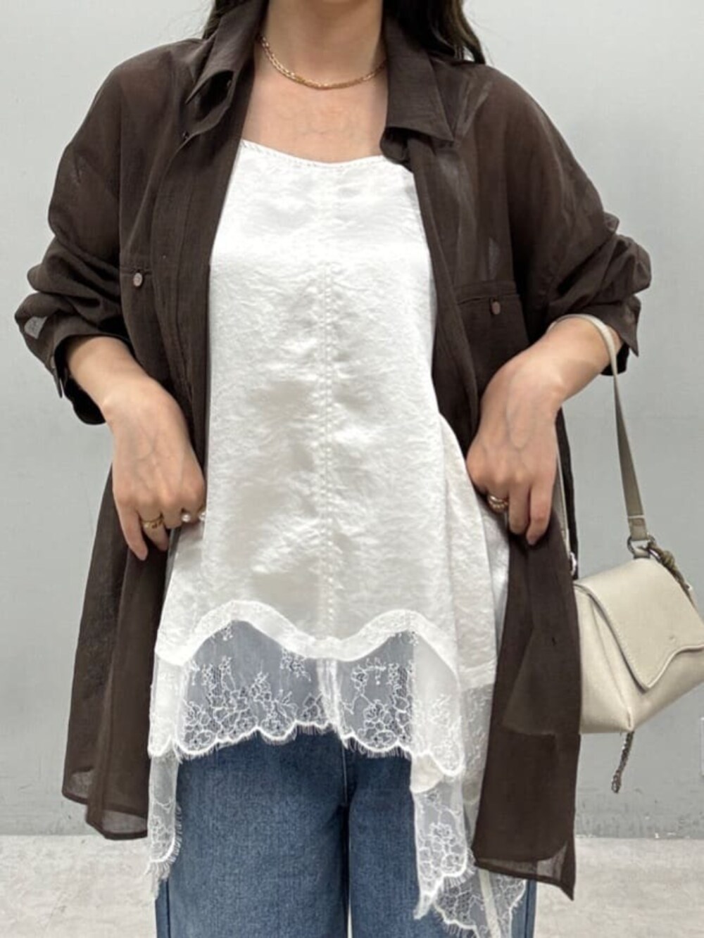 ホワイト系のショルダーバッグ、ブラウン系のシャツ/ブラウス、ブルー系のデニムパンツを着用したレディースの夏コーディネートの2枚目の写真
