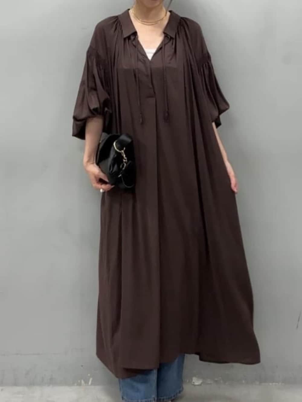 ブラック系のショルダーバッグ、ブルー系のデニムパンツ、ブラウン系のワンピースを着用したレディースの夏コーディネートの2枚目の写真