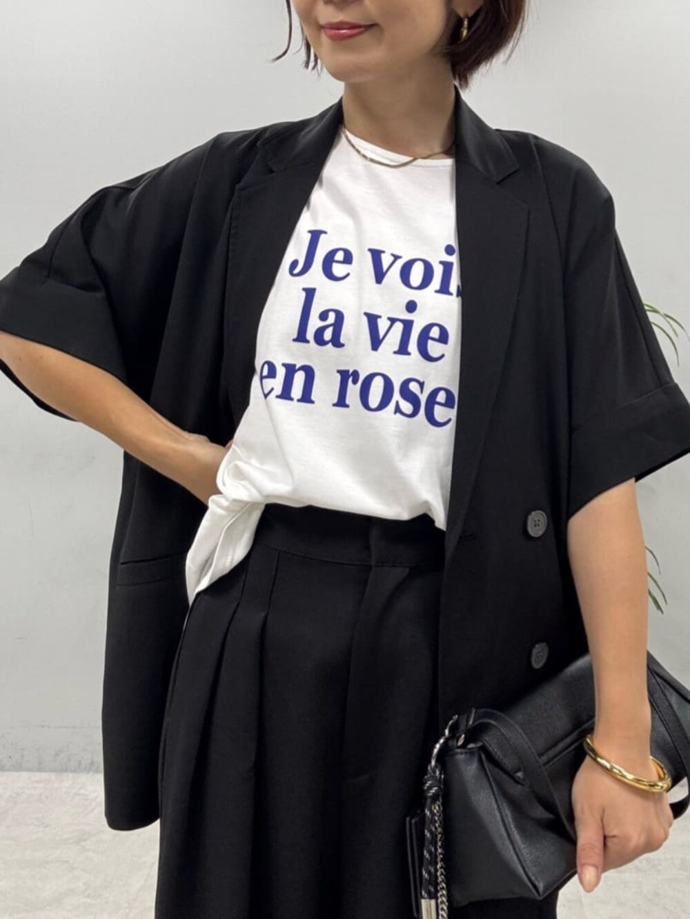 ブラック系のショルダーバッグ、ブラック系のシャツ/ブラウス、ホワイト系のTシャツ/カットソーを着用したレディースの夏コーディネートの2枚目の写真