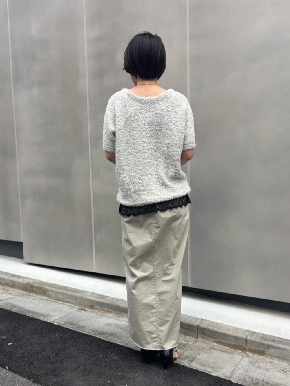 ブラック系のキャミソール、ベージュ系のスカート、ブラック系のショルダーバッグを着用したレディースの春コーディネートの5枚目の写真