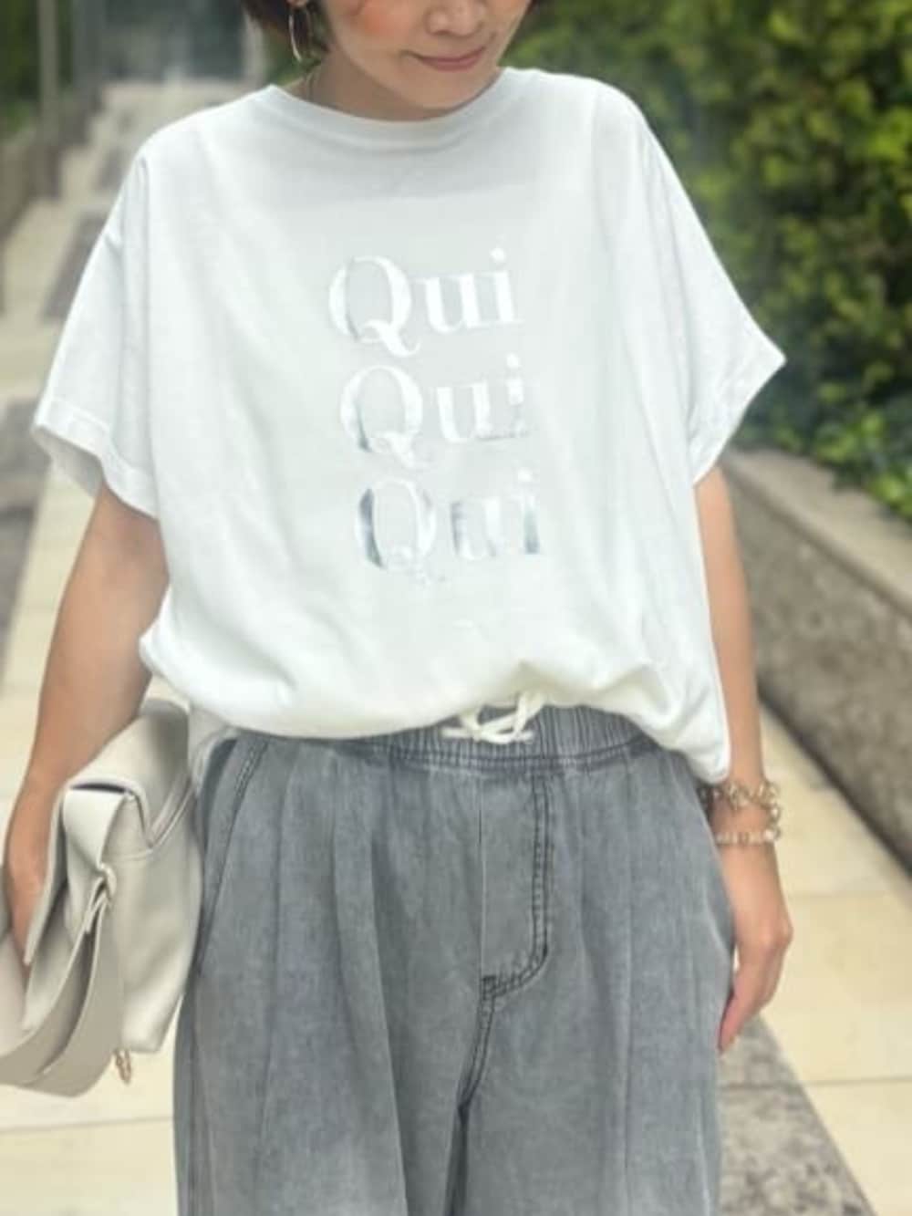 ホワイト系のショルダーバッグ、ホワイト系のTシャツ/カットソー、ブラック系のデニムパンツを着用したレディースの夏コーディネートの3枚目の写真