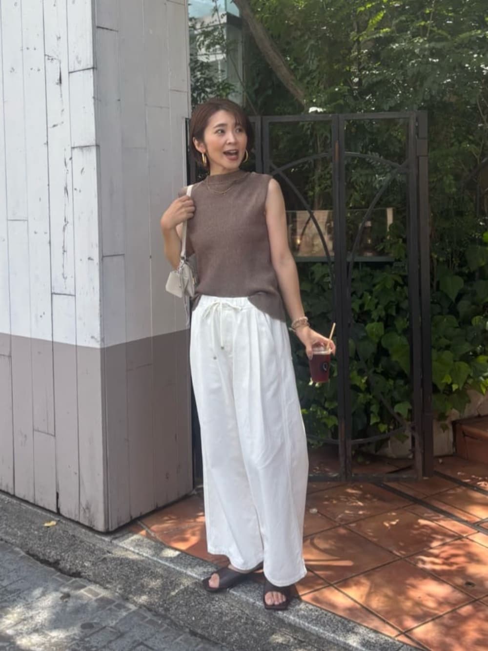 ホワイト系のショルダーバッグ、ホワイト系のデニムパンツ、ブラウン系のニット/セーターを着用したレディースの夏コーディネートの3枚目の写真