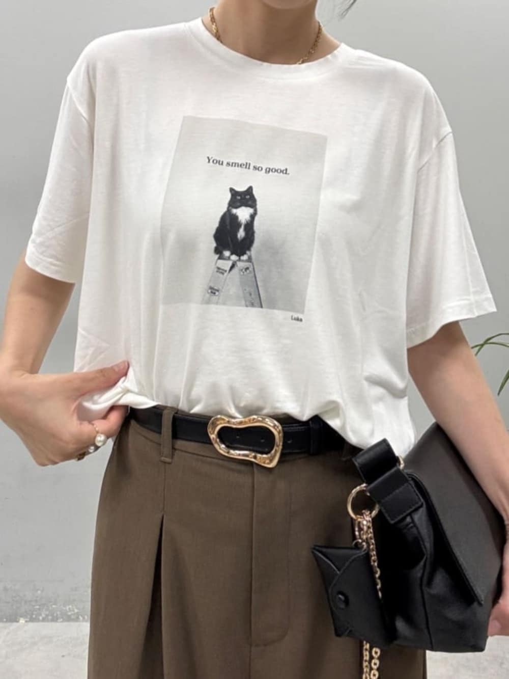 ブラウン系のスラックス、ブラウン系のショルダーバッグ、その他のTシャツ/カットソーを着用したレディースの夏コーディネートの2枚目の写真