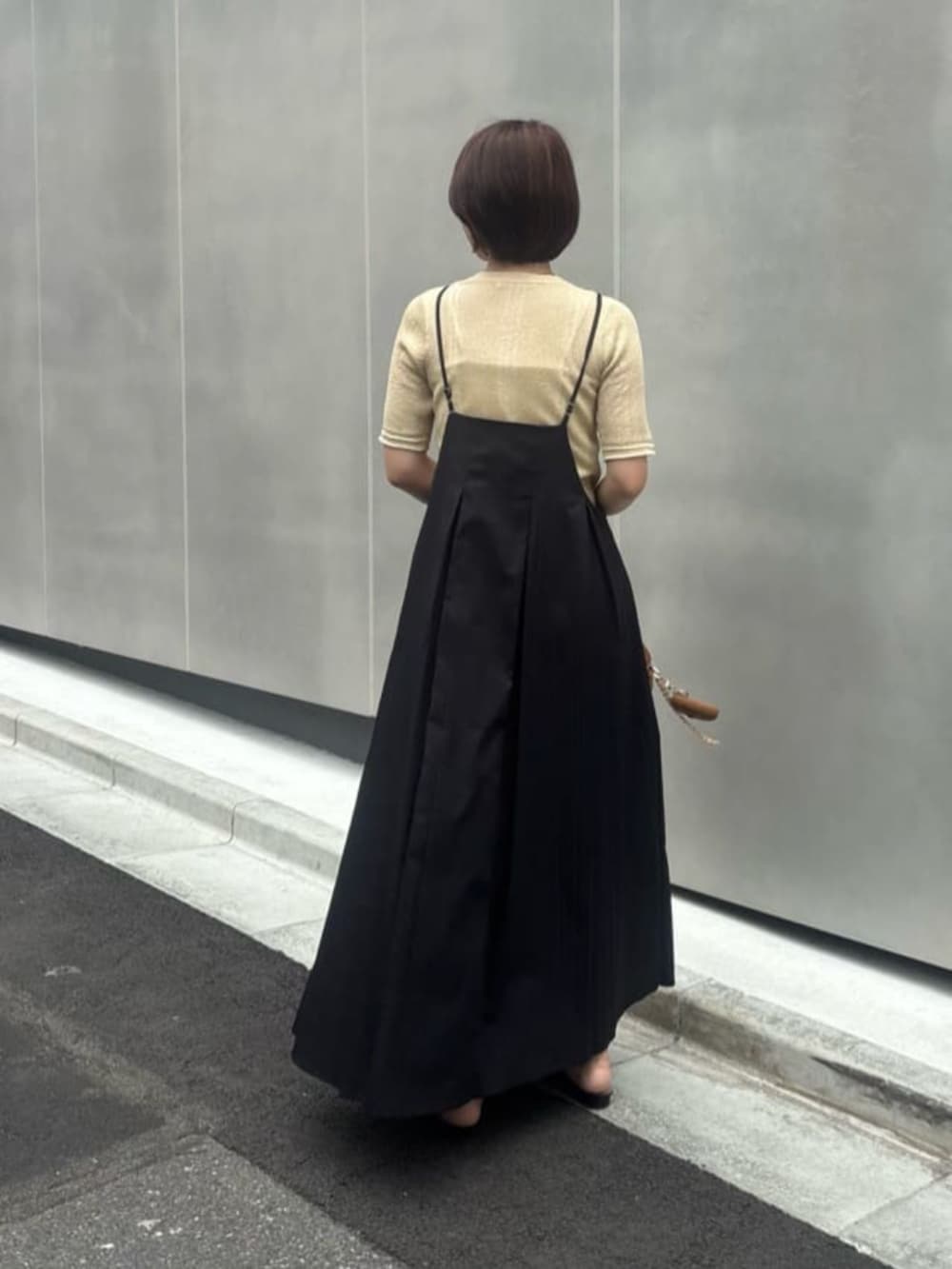 イエロー系のショルダーバッグ、ブラック系のワンピース、ゴールド系のニット/セーターを着用したレディースの夏コーディネートの3枚目の写真
