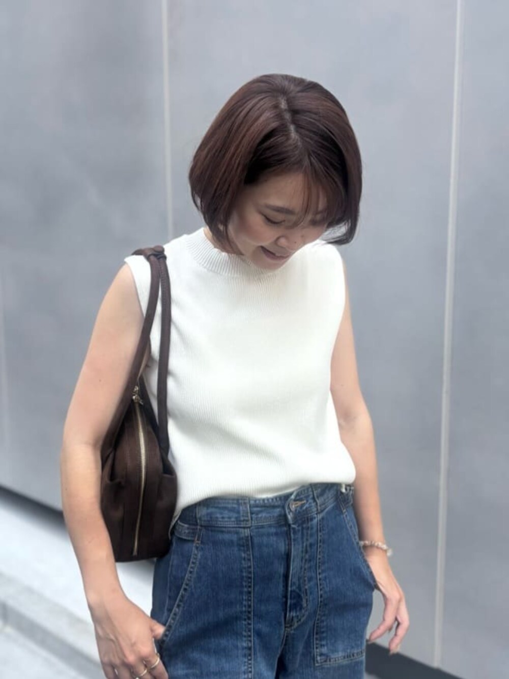 ブルー系のデニムパンツ、ホワイト系のニット/セーター、ブラウン系のボストンバッグを着用したレディースの夏コーディネートの4枚目の写真