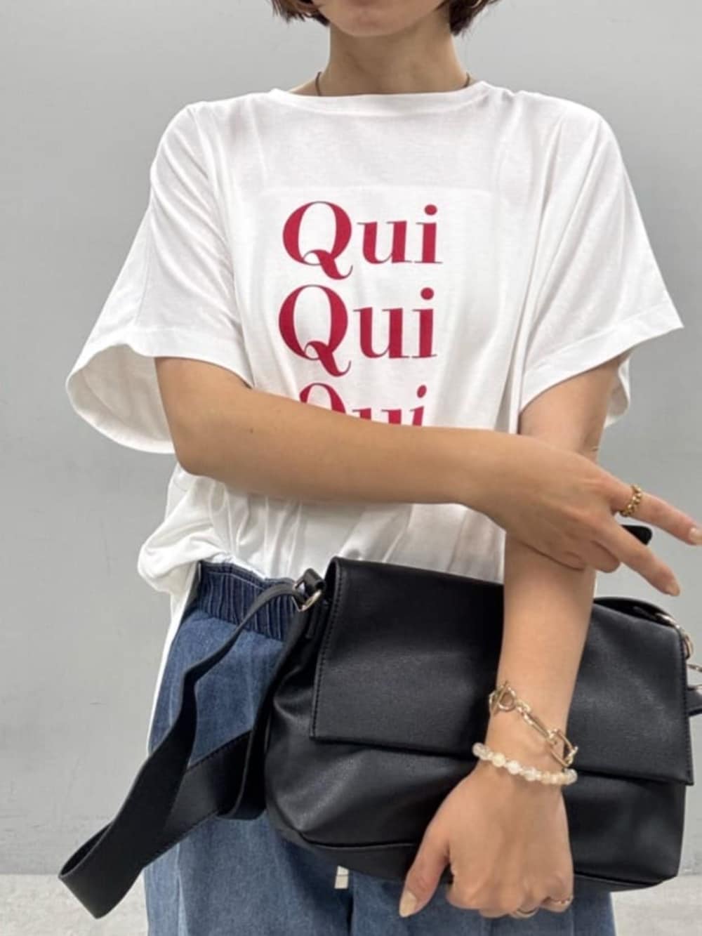 ブラック系のショルダーバッグ、ホワイト系のTシャツ/カットソー、ブルー系のデニムパンツを着用したレディースの夏コーディネートの3枚目の写真