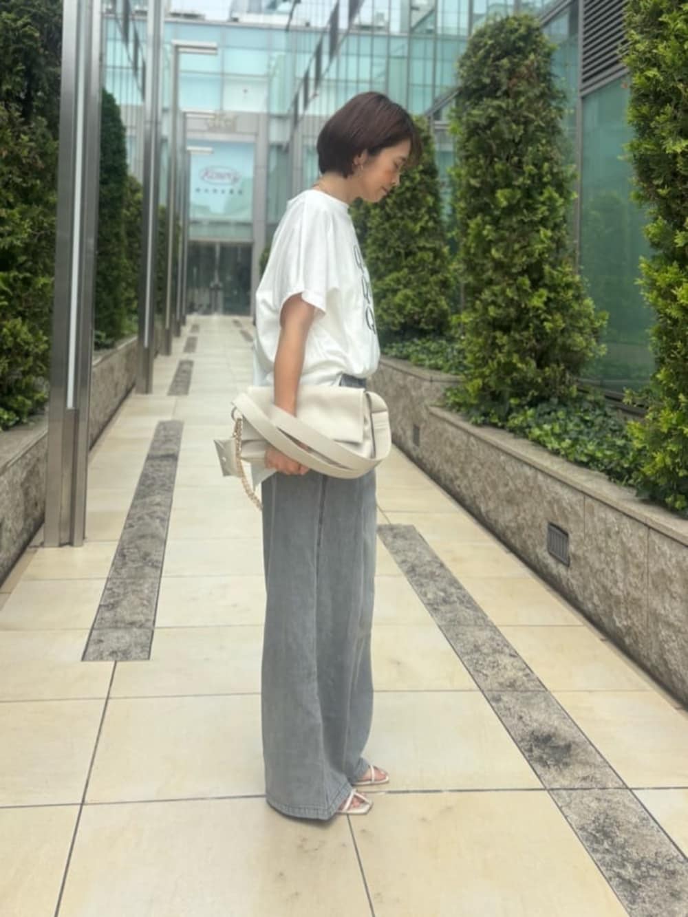 ホワイト系のショルダーバッグ、ホワイト系のTシャツ/カットソー、ブラック系のデニムパンツを着用したレディースの夏コーディネートの2枚目の写真