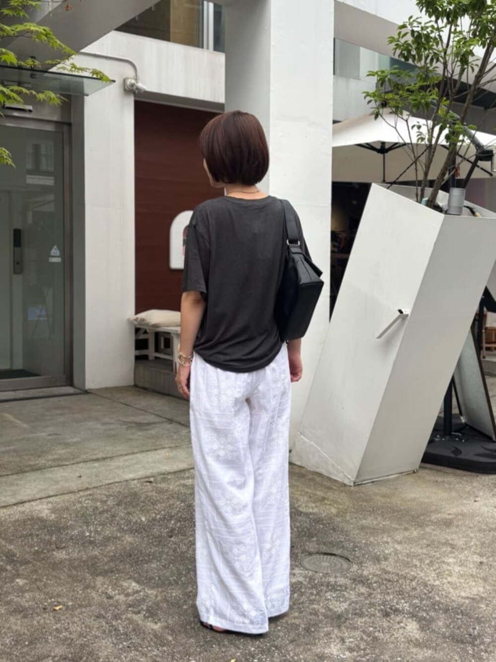 ブラック系のショルダーバッグ、ホワイト系のその他パンツ、その他のTシャツ/カットソーを着用したレディースの夏コーディネートの3枚目の写真