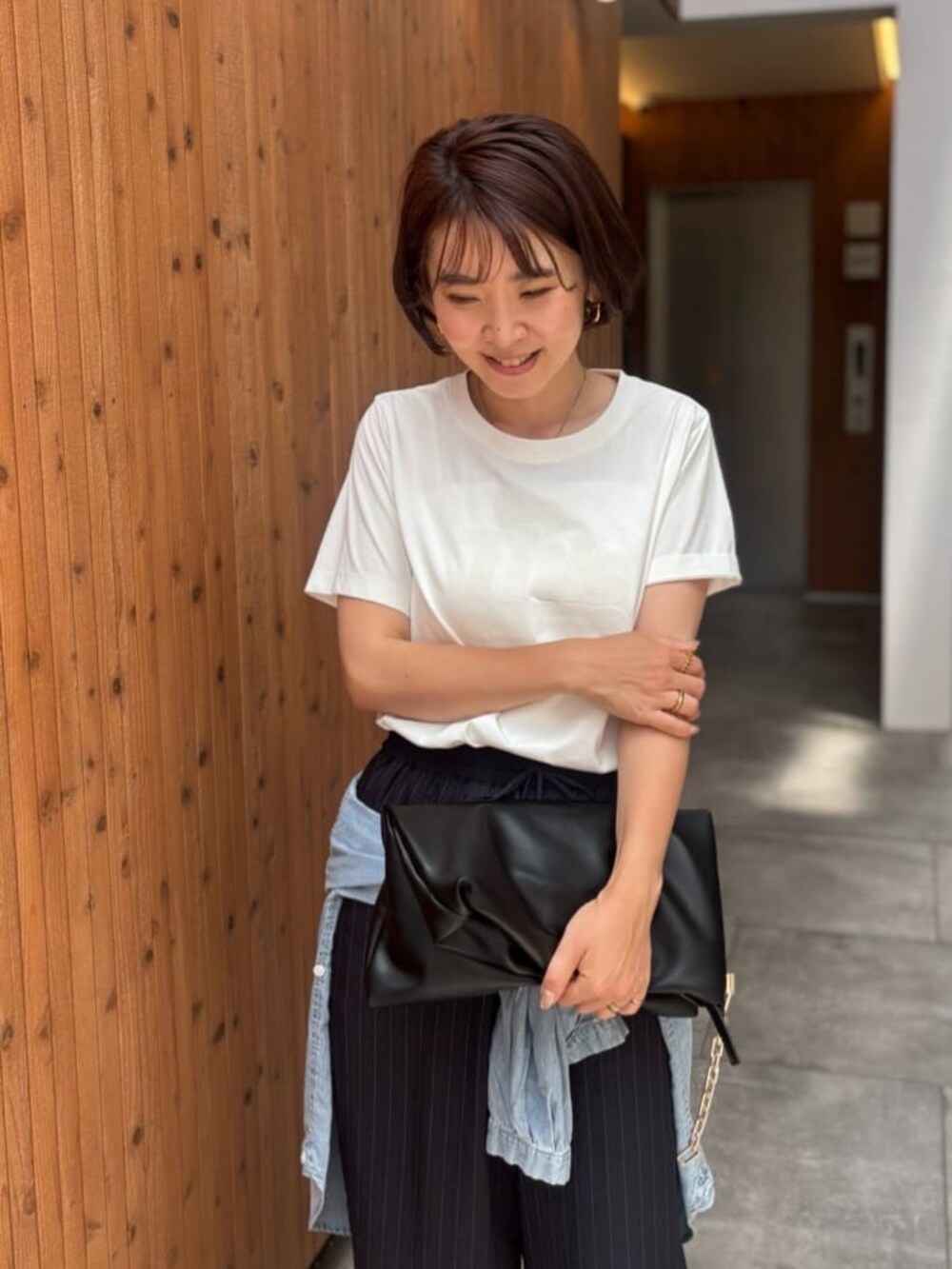 ブラック系のショルダーバッグ、ブルー系のシャツ/ブラウス、ホワイト系のTシャツ/カットソーを着用したレディースの夏コーディネートの3枚目の写真