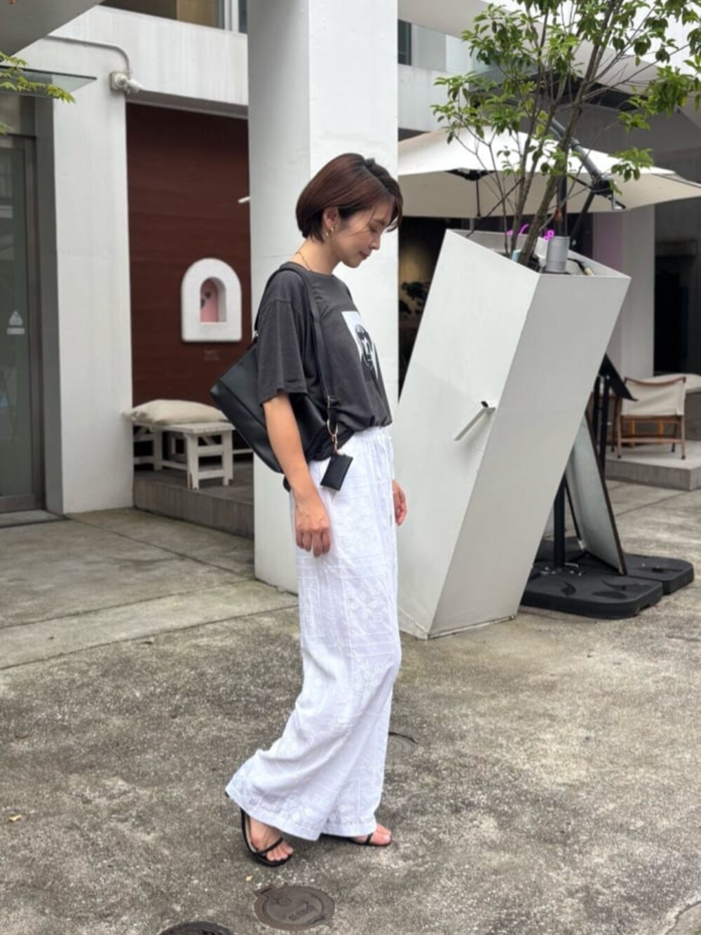 ブラック系のショルダーバッグ、ホワイト系のその他パンツ、その他のTシャツ/カットソーを着用したレディースの夏コーディネートの2枚目の写真