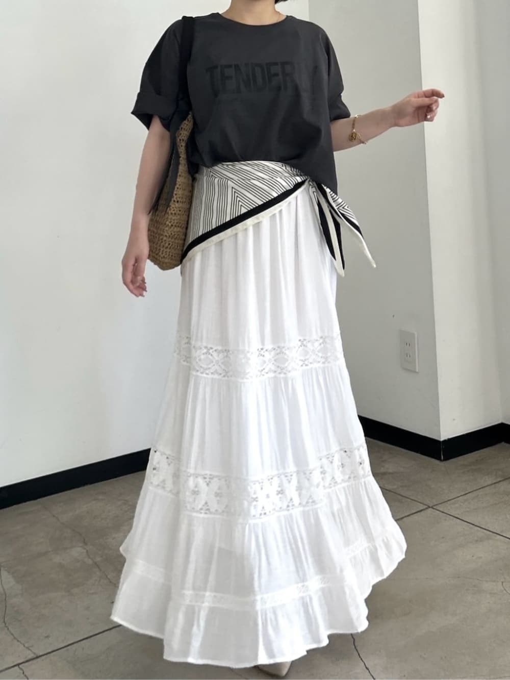 ホワイト系のスカート、ブラック系のTシャツ/カットソーを着用したレディースの春コーディネートの2枚目の写真
