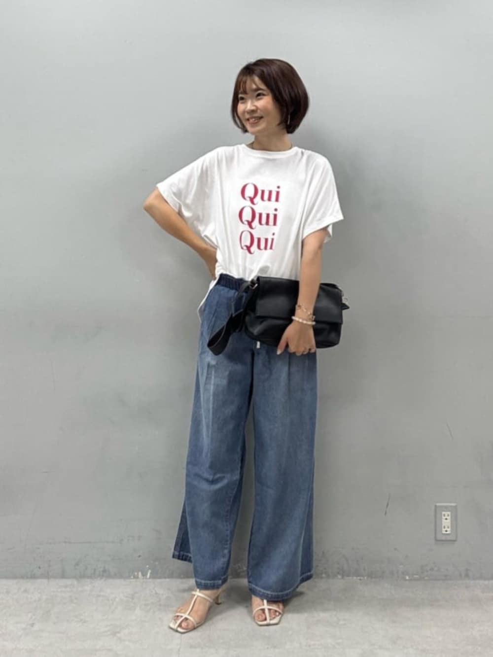 ブラック系のショルダーバッグ、ホワイト系のTシャツ/カットソー、ブルー系のデニムパンツを着用したレディースの夏コーディネートの2枚目の写真