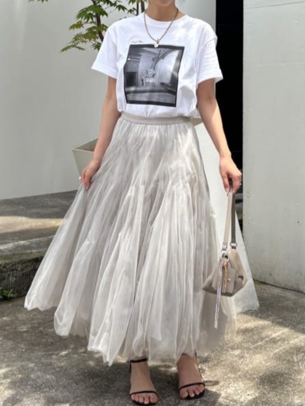 ベージュ系のショルダーバッグ、ホワイト系のTシャツ/カットソー、ベージュ系のスカートを着用したレディースの夏コーディネートの4枚目の写真
