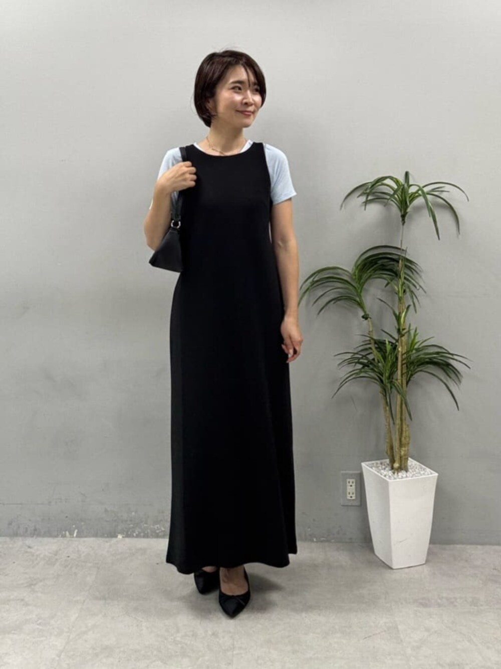 ブラック系のショルダーバッグ、ブラック系のワンピース、ブルー系のTシャツ/カットソーを着用したレディースの春コーディネートの2枚目の写真