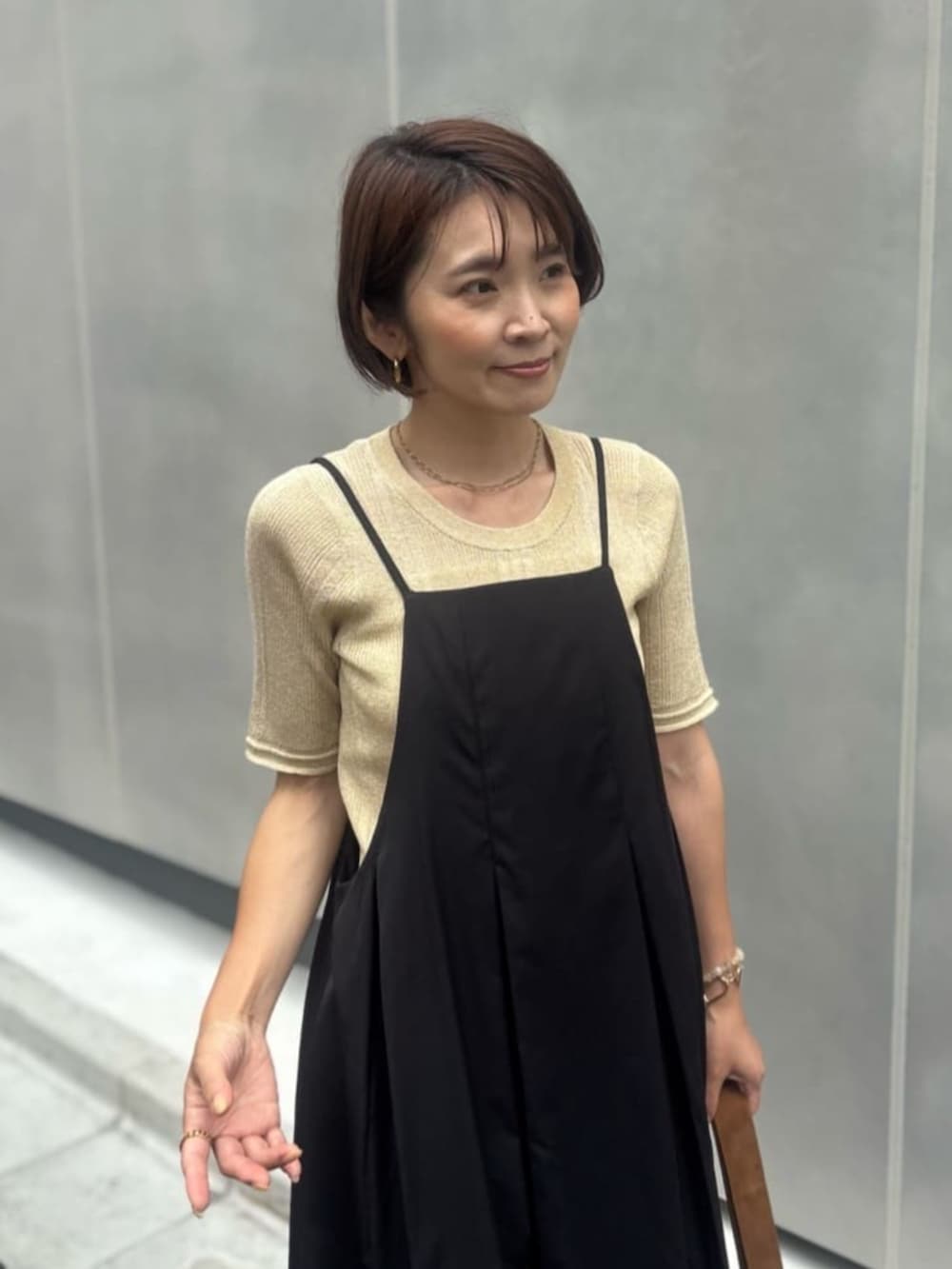 イエロー系のショルダーバッグ、ブラック系のワンピース、ゴールド系のニット/セーターを着用したレディースの夏コーディネートの4枚目の写真