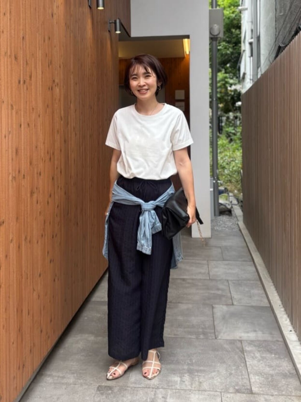 ブラック系のショルダーバッグ、ブルー系のシャツ/ブラウス、ホワイト系のTシャツ/カットソーを着用したレディースの夏コーディネートの2枚目の写真