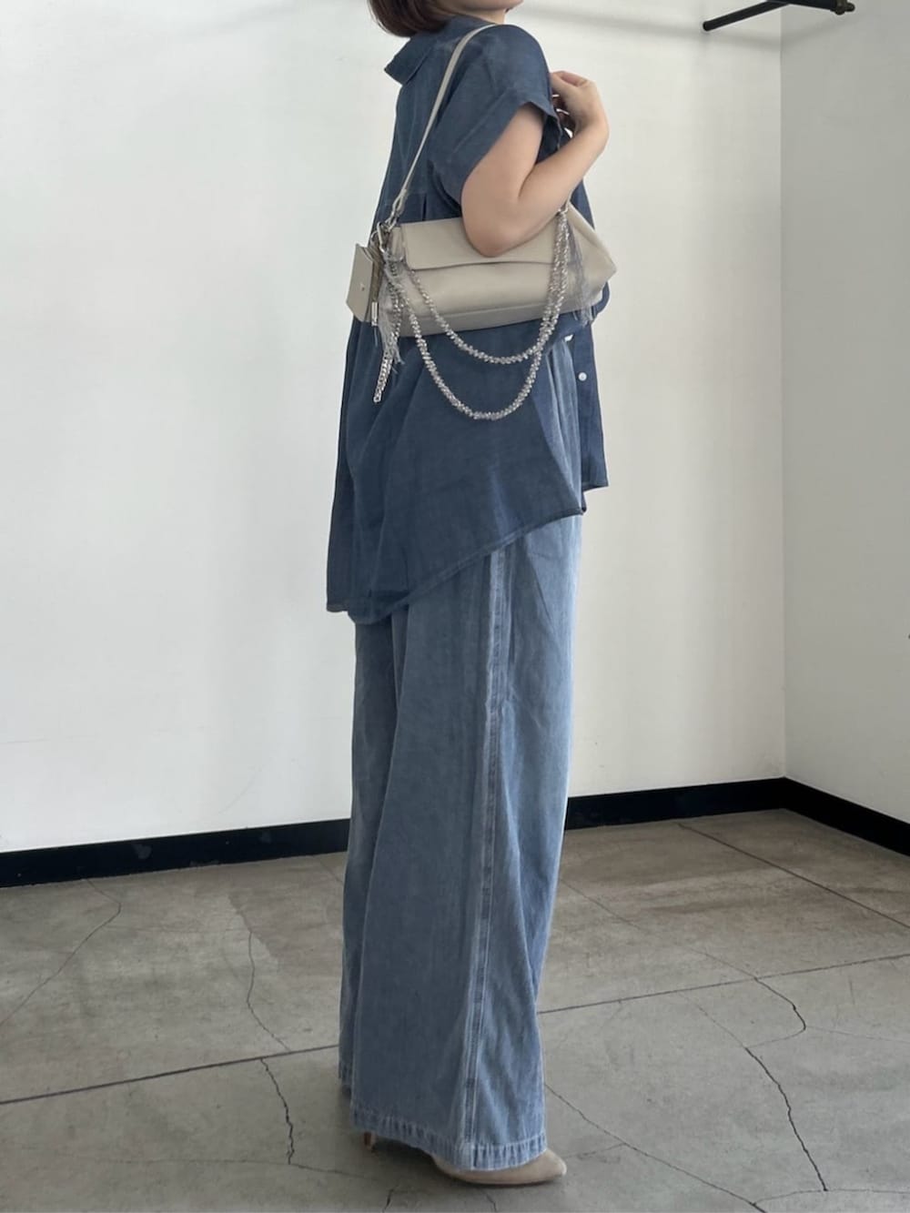 ホワイト系のショルダーバッグ、ブルー系のシャツ/ブラウス、ブルー系のデニムパンツを着用したレディースの夏コーディネートの3枚目の写真