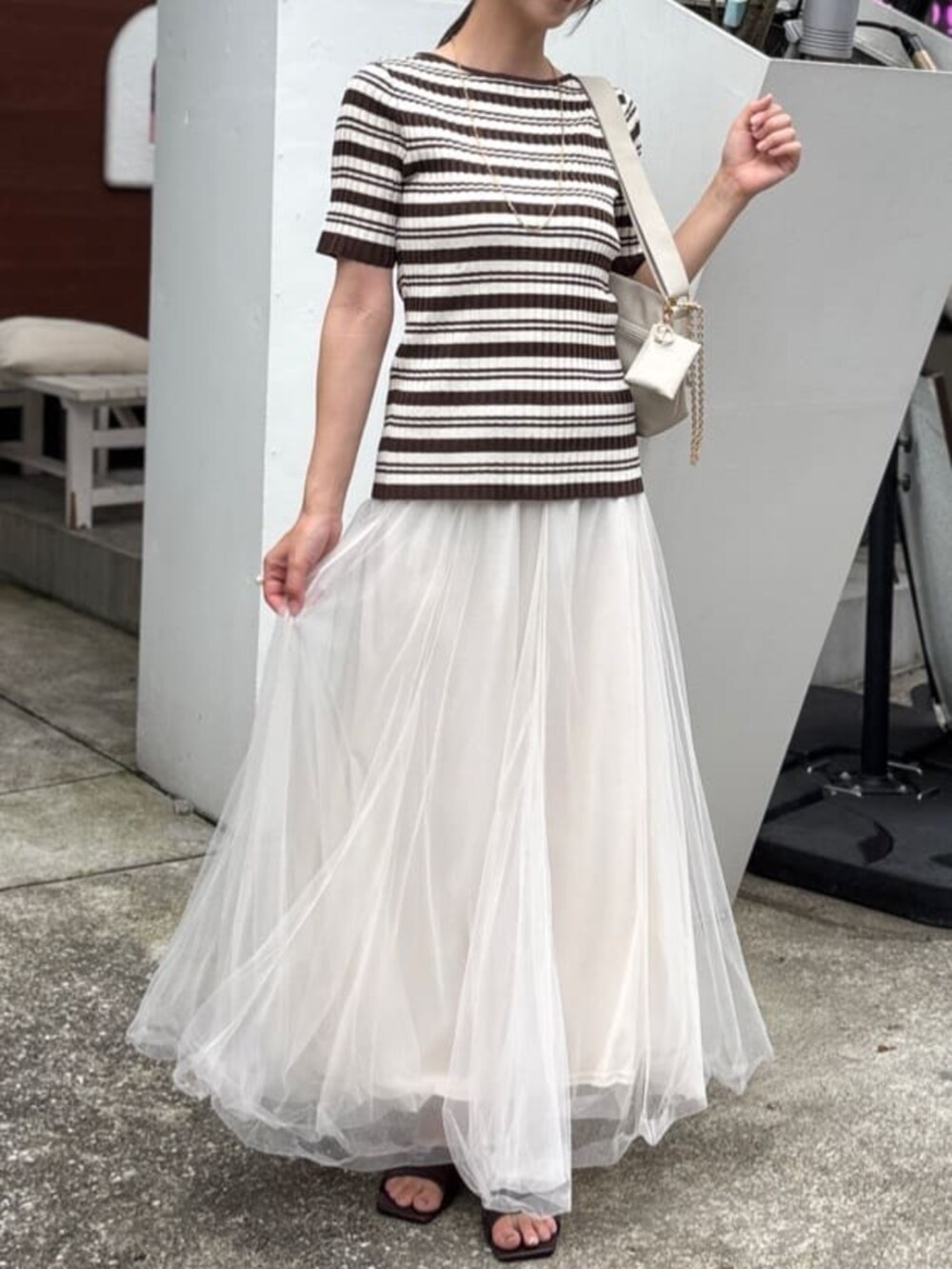 ホワイト系のショルダーバッグ、ブラウン系のニット/セーター、ホワイト系のスカートを着用したレディースの夏コーディネートの2枚目の写真