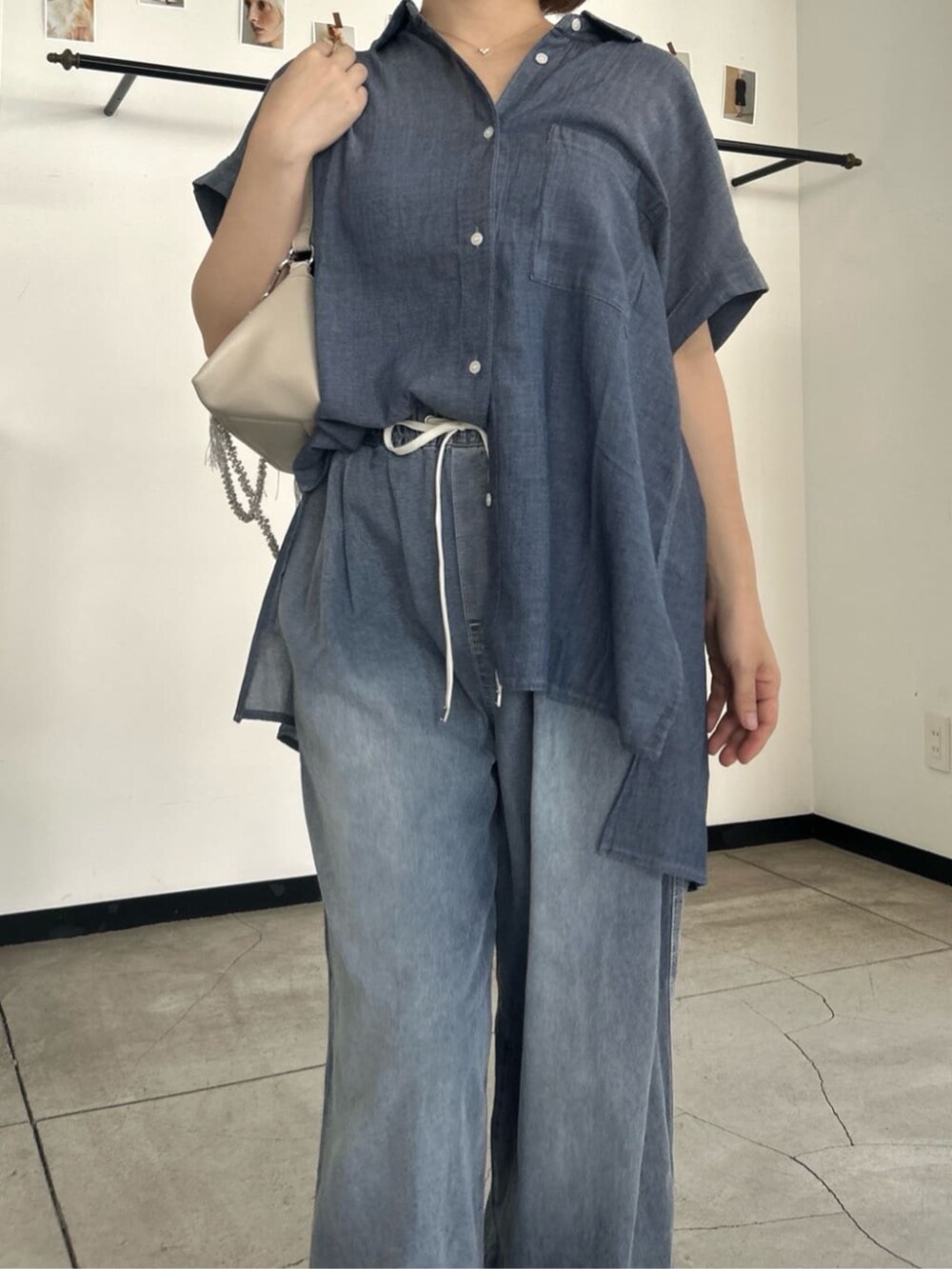 ホワイト系のショルダーバッグ、ブルー系のシャツ/ブラウス、ブルー系のデニムパンツを着用したレディースの夏コーディネートの2枚目の写真