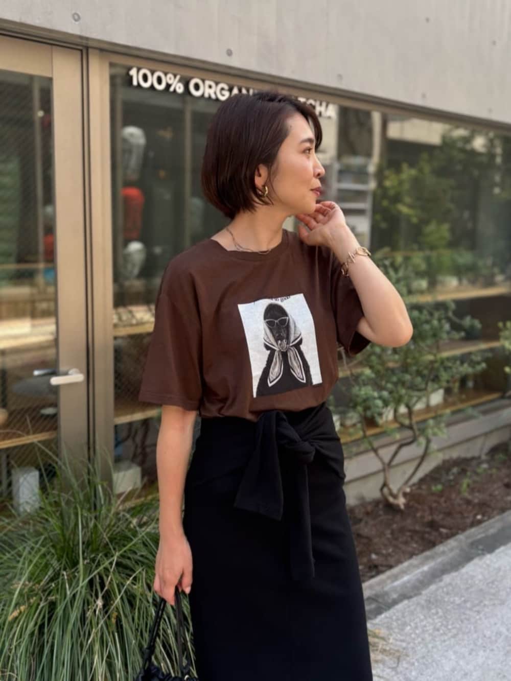ブラック系のスカート、ブラウン系のTシャツ/カットソーを着用したレディースの夏コーディネートの2枚目の写真