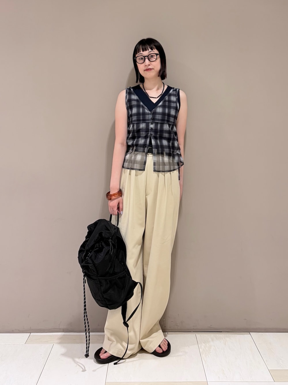 ベージュ系のその他パンツ、ブルー系のタンクトップ、ブラック系のバックパック/リュックを着用したレディースの夏コーディネートの2枚目の写真